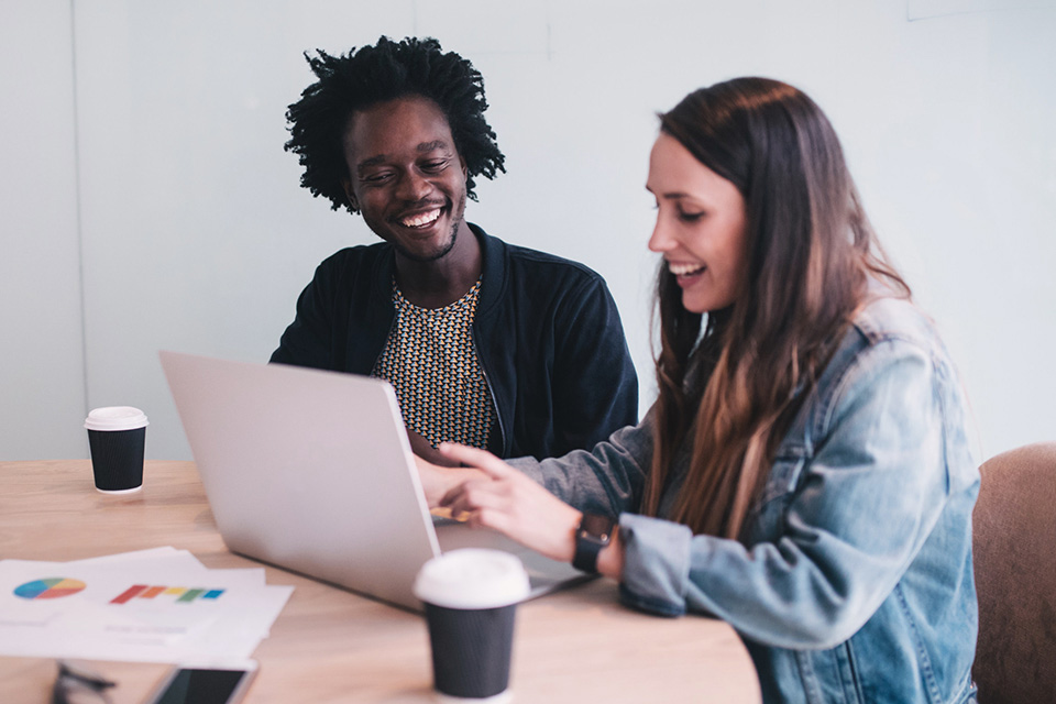 Creator and marketer talking by a laptop