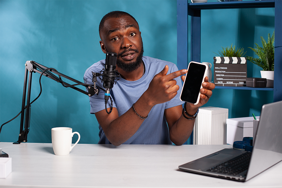 Influencer pointing at a smartphone while speaking into a microphone