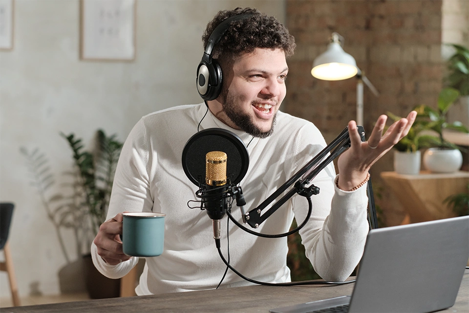Influencer with a mug talking and gesticulating in front of a mic and laptop