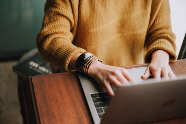 person in a sweater typing on a laptop starting the work toward a long-term influencer partnership