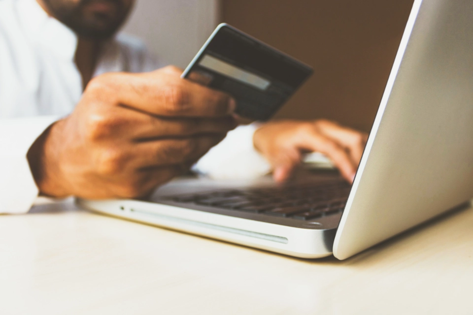 Someone holding a credit card in front of a laptop