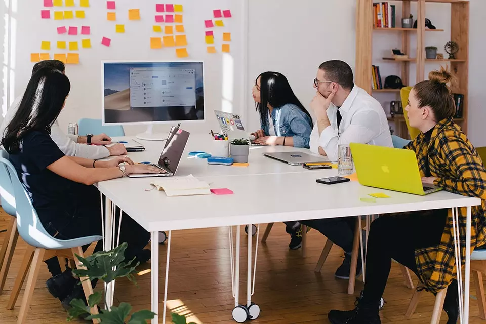Group of marketers at a table reviewing something on a monitor
